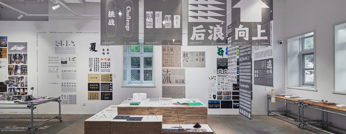 Gallery exhibition with graphic design posters hanging above display tables.